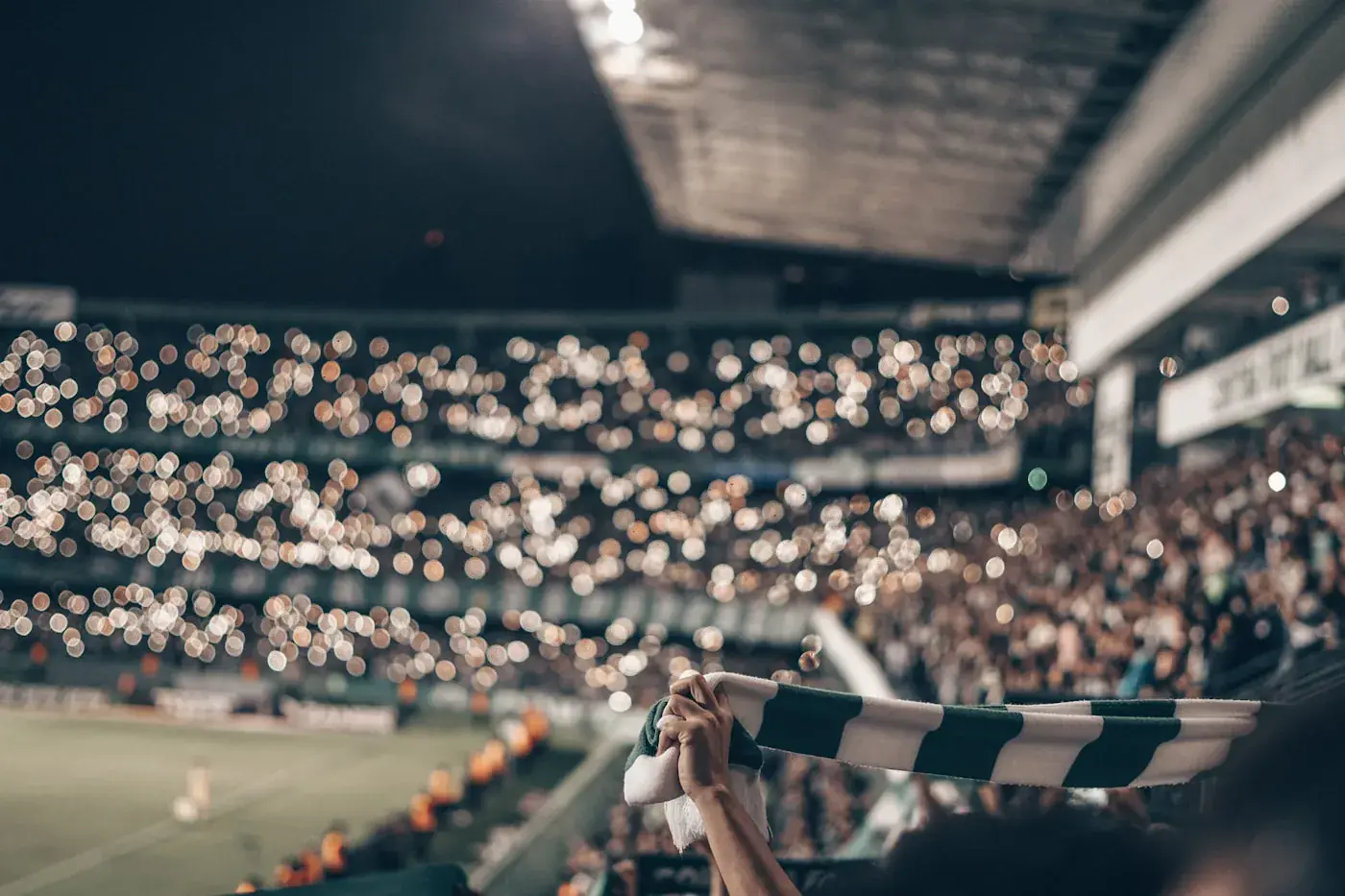 A supporter raises a club scarf in a packed stand
