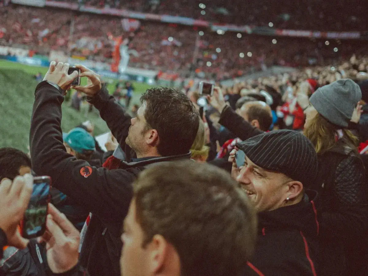 Supporters with phones raised in a packed stand on matchday
